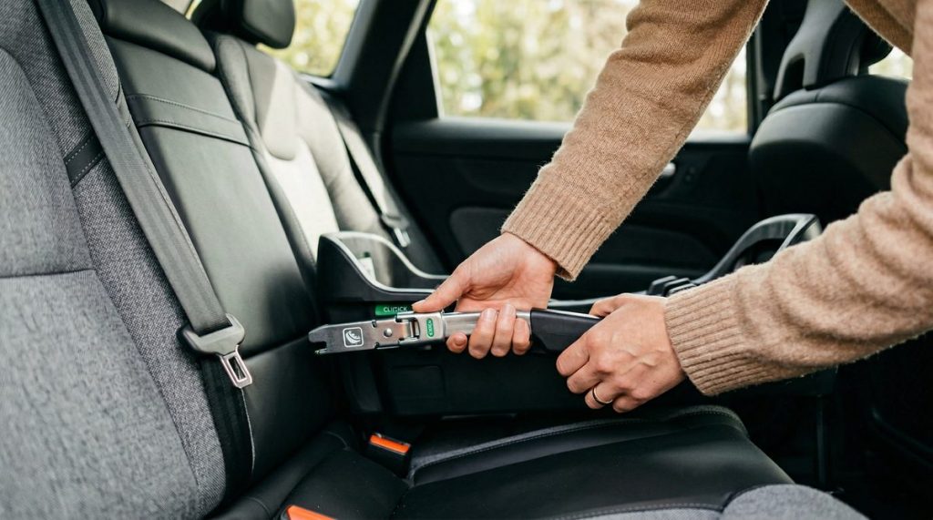 Mains d'un parent installant un siège auto avec le système ISOFIX dans une voiture